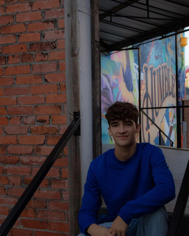 Jaden Duhon sitting on steps in front of a mural